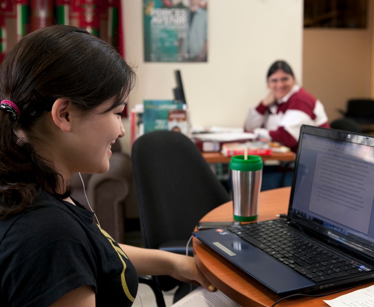 woman at laptop with ponytail smiling