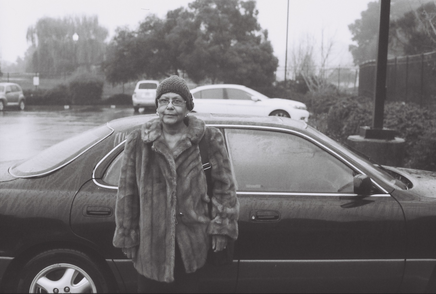 Black woman in fur coat standing next to car in the rain